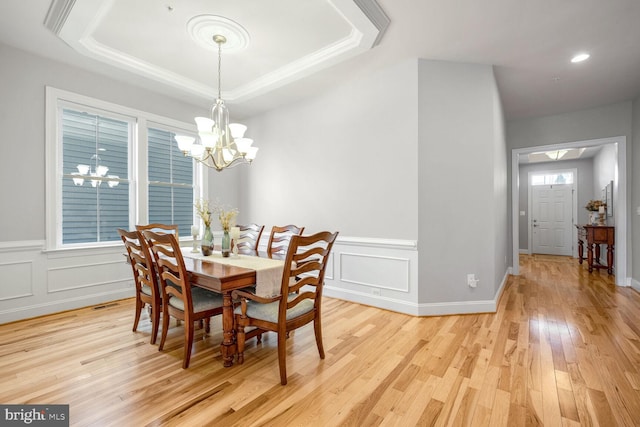 dining space featuring plenty of natural light, light hardwood / wood-style flooring, a notable chandelier, and a tray ceiling