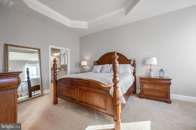 bedroom featuring crown molding, a tray ceiling, ensuite bath, and light colored carpet