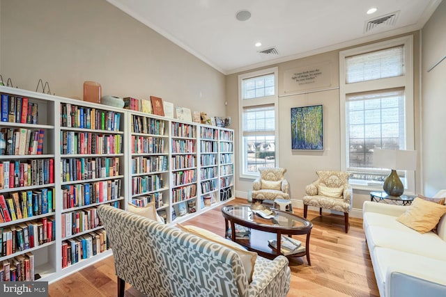 sitting room with crown molding and light hardwood / wood-style flooring