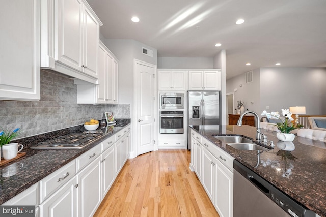 kitchen featuring white cabinetry, sink, stainless steel appliances, and dark stone counters