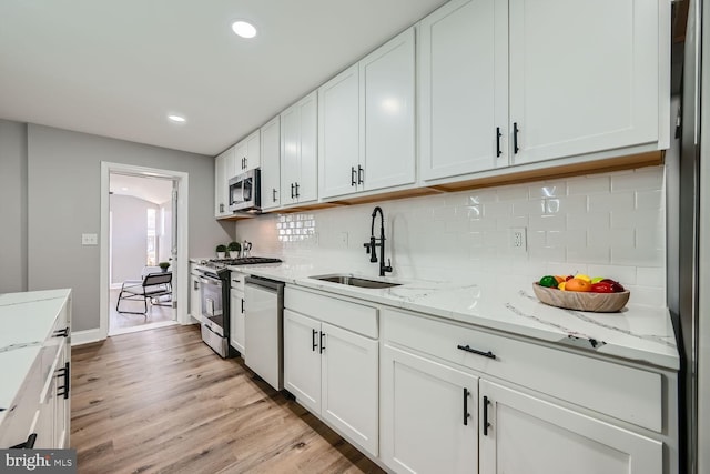 kitchen featuring appliances with stainless steel finishes, sink, white cabinets, and light hardwood / wood-style flooring