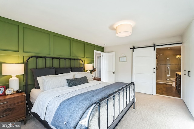 bedroom featuring light colored carpet and a barn door