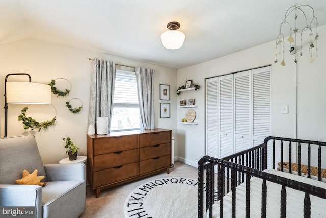 bedroom featuring a crib, light colored carpet, a closet, and vaulted ceiling