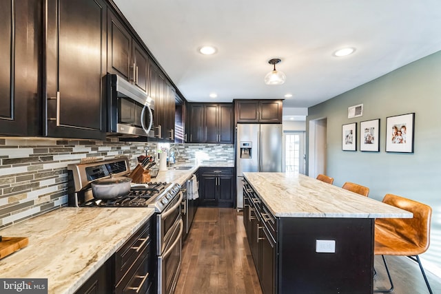 kitchen featuring stainless steel appliances, hanging light fixtures, sink, and a breakfast bar area