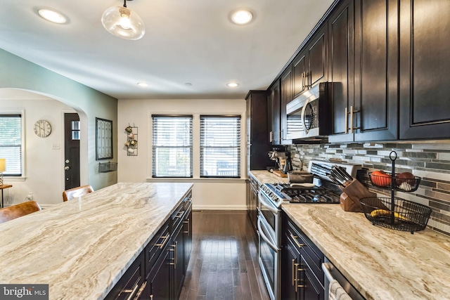 kitchen featuring light stone counters, stainless steel appliances, dark wood-type flooring, and tasteful backsplash