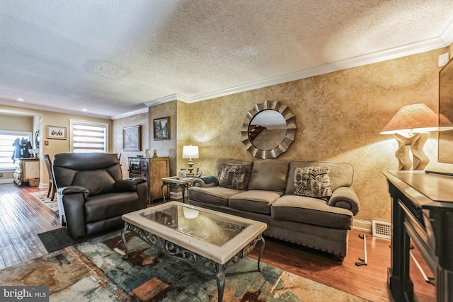 living room with ornamental molding, wood-type flooring, and a textured ceiling