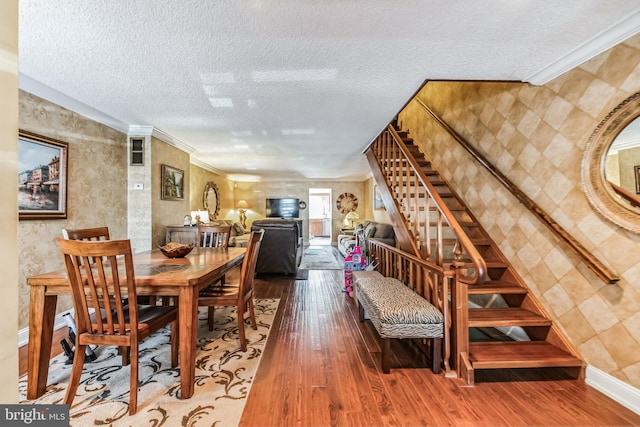 dining room featuring crown molding, wood-type flooring, and a textured ceiling