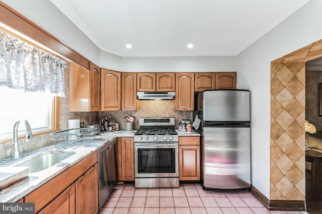 kitchen featuring sink, decorative backsplash, light tile patterned floors, and appliances with stainless steel finishes