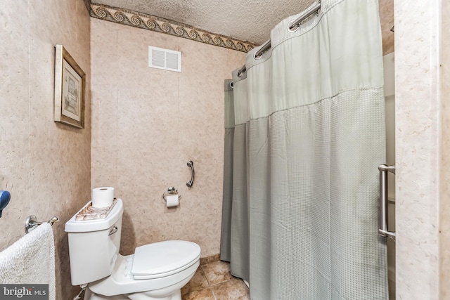 bathroom with a shower with curtain, toilet, tile patterned flooring, and a textured ceiling