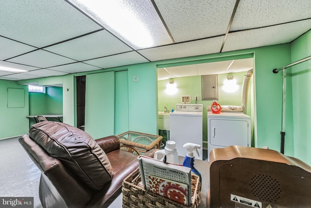 basement featuring separate washer and dryer, a paneled ceiling, and electric panel