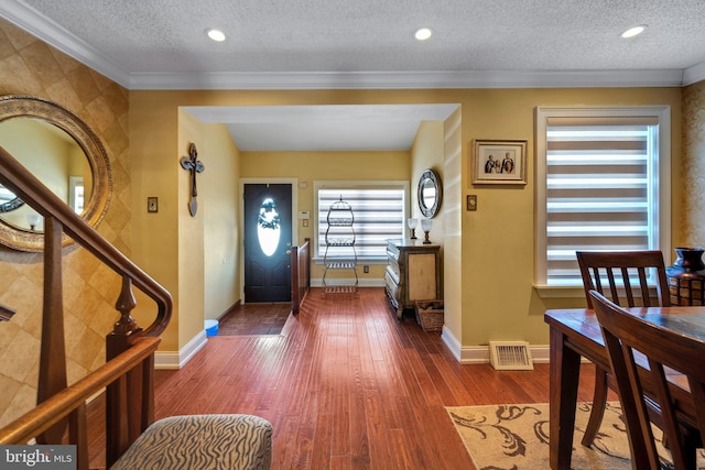 entryway with crown molding, hardwood / wood-style floors, and a textured ceiling