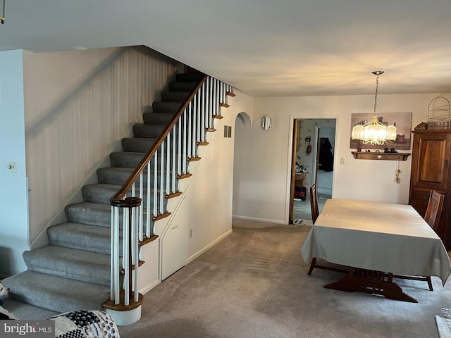 staircase featuring a chandelier and carpet floors