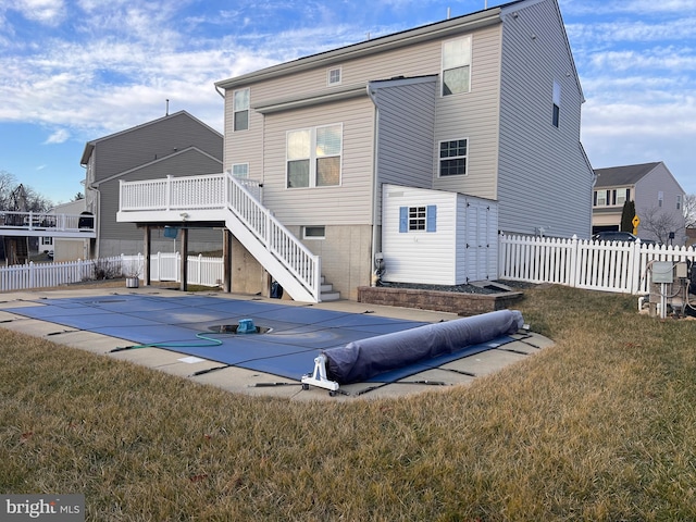 rear view of property with a pool side deck and a yard