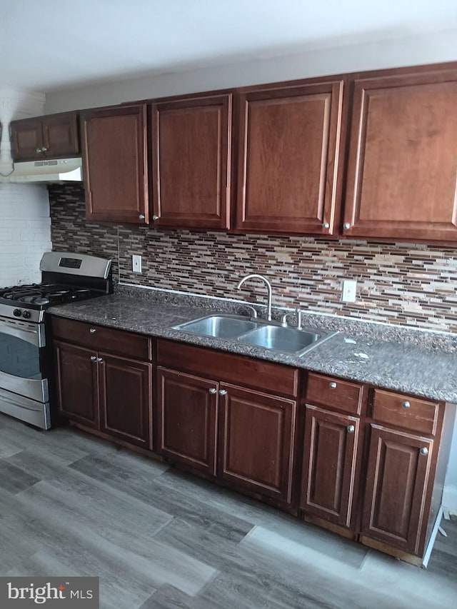 kitchen featuring gas range, sink, light hardwood / wood-style flooring, and decorative backsplash