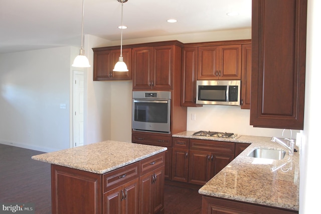 kitchen with sink, light stone counters, a center island, pendant lighting, and stainless steel appliances