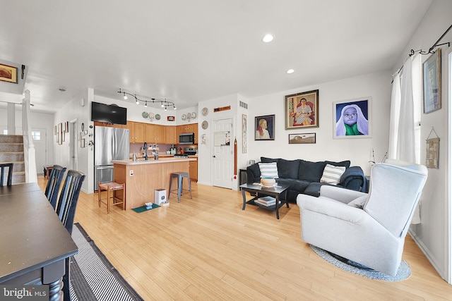 living room with a wealth of natural light, track lighting, and light wood-type flooring