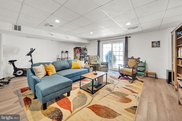 living room featuring a paneled ceiling and light wood-type flooring