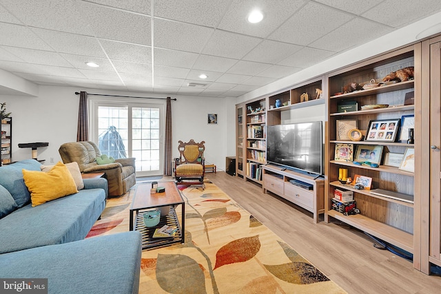 living room featuring a paneled ceiling and light hardwood / wood-style flooring