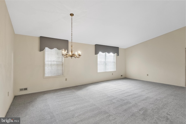 carpeted spare room featuring a notable chandelier