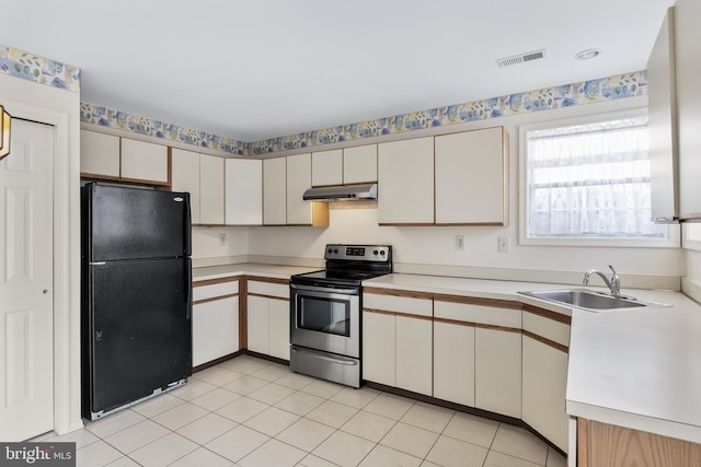 kitchen with black fridge, stainless steel range with electric stovetop, sink, and light tile patterned floors