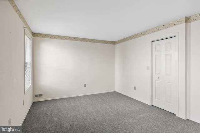 unfurnished room featuring dark colored carpet