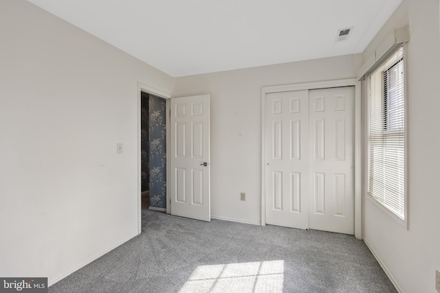 unfurnished bedroom with multiple windows, light carpet, and a closet