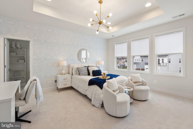 carpeted bedroom featuring an inviting chandelier and a tray ceiling