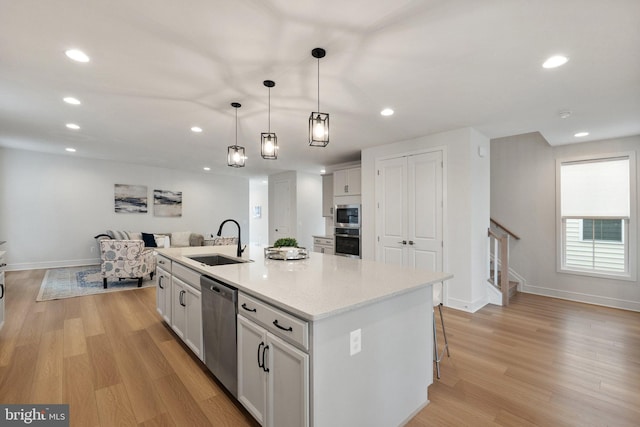 kitchen featuring decorative light fixtures, white cabinetry, sink, a kitchen island with sink, and stainless steel appliances