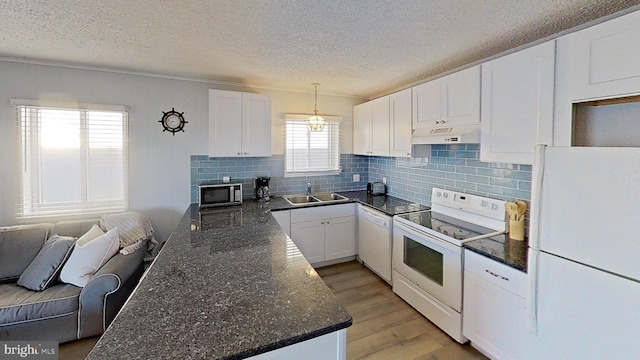 kitchen with sink, white cabinetry, decorative light fixtures, dark stone countertops, and white appliances