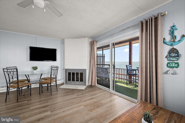 interior space with a brick fireplace, ceiling fan, a textured ceiling, and light wood-type flooring