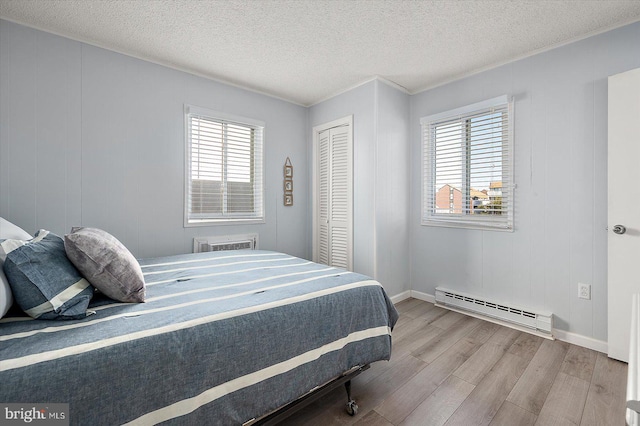 bedroom featuring light hardwood / wood-style flooring, a baseboard radiator, a closet, and a textured ceiling