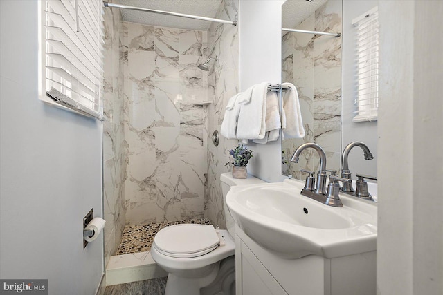 bathroom featuring tiled shower, vanity, and toilet