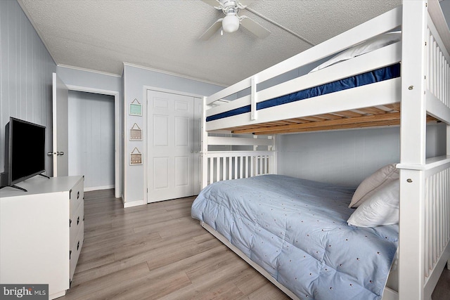 bedroom featuring ceiling fan, crown molding, a textured ceiling, and light wood-type flooring