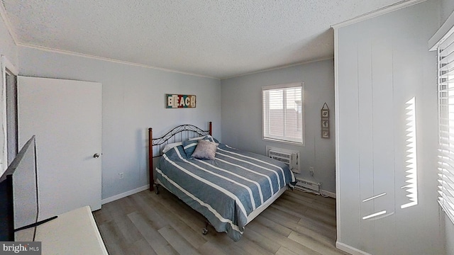 bedroom featuring a wall mounted air conditioner, hardwood / wood-style flooring, a baseboard heating unit, crown molding, and a textured ceiling