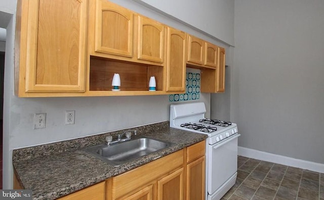 kitchen featuring dark stone countertops, sink, and white gas range oven