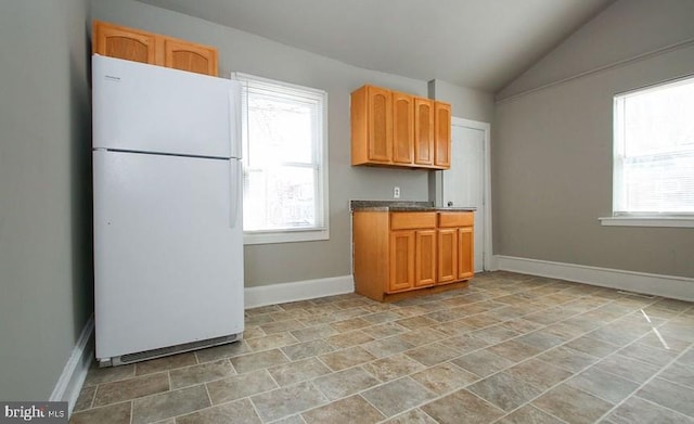 kitchen with vaulted ceiling and white fridge