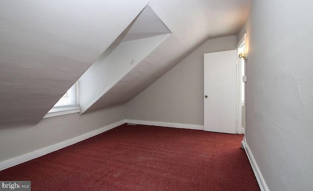 bonus room featuring dark carpet and vaulted ceiling