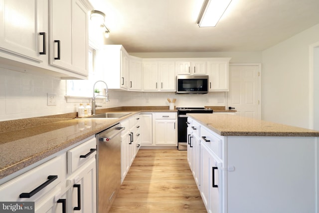 kitchen with stainless steel appliances, light stone countertops, sink, and white cabinets