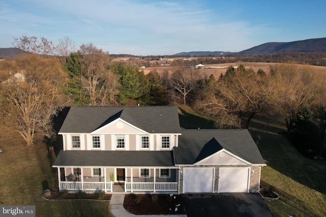 view of front facade with a garage, a mountain view, and covered porch