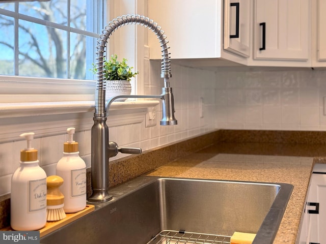 interior details featuring white cabinetry, sink, and tasteful backsplash