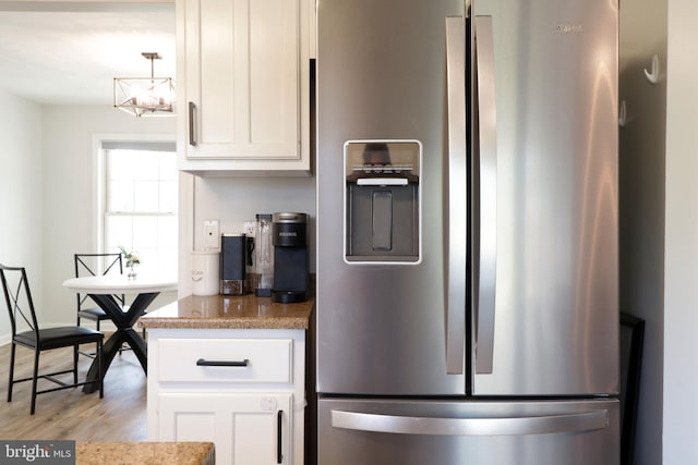 kitchen with stainless steel refrigerator with ice dispenser, white cabinetry, light hardwood / wood-style floors, and pendant lighting