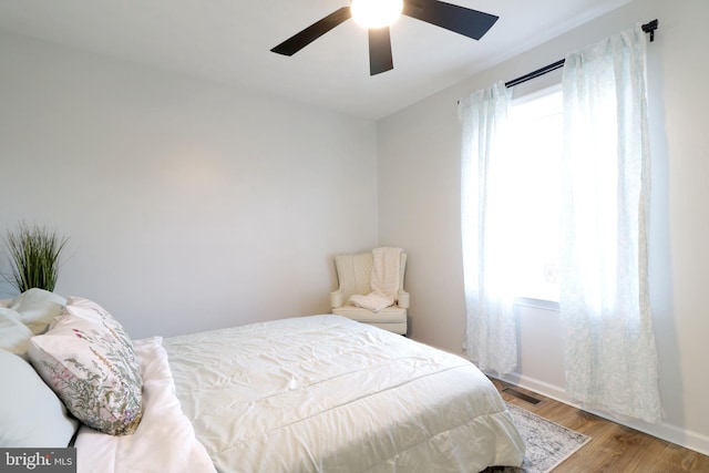 bedroom featuring multiple windows, hardwood / wood-style flooring, and ceiling fan