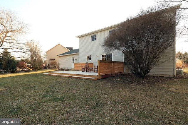 rear view of property featuring a playground, a yard, a deck, and central air condition unit