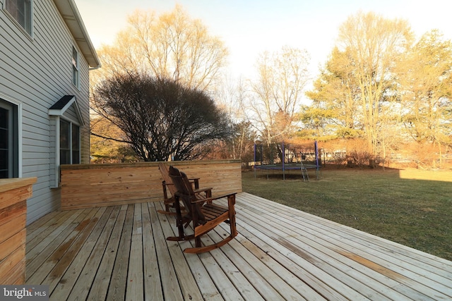 wooden deck with a trampoline and a yard