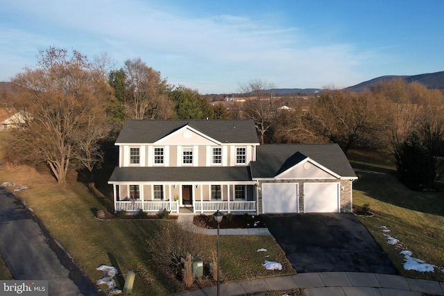 view of front of house with a mountain view, a garage, a front yard, and covered porch