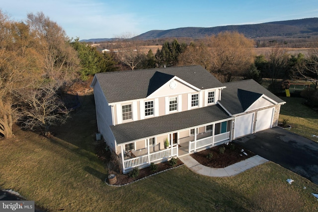 view of front of home featuring a garage, a mountain view, a front yard, and covered porch