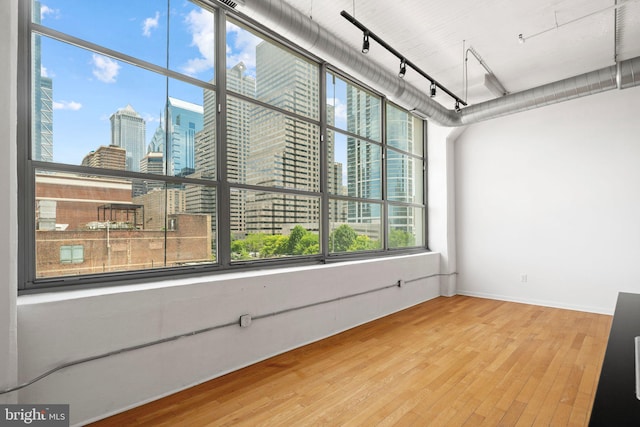 spare room with hardwood / wood-style flooring, track lighting, and a healthy amount of sunlight