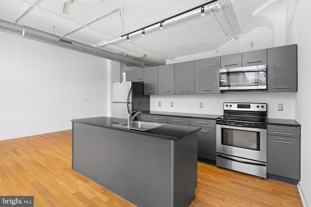 kitchen with light hardwood / wood-style floors, stainless steel appliances, gray cabinets, and sink