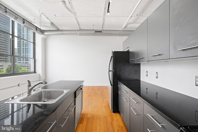 kitchen with stainless steel appliances, gray cabinets, sink, and light hardwood / wood-style flooring