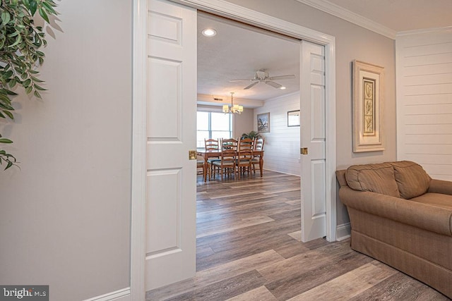 hall with hardwood / wood-style flooring, crown molding, and a notable chandelier